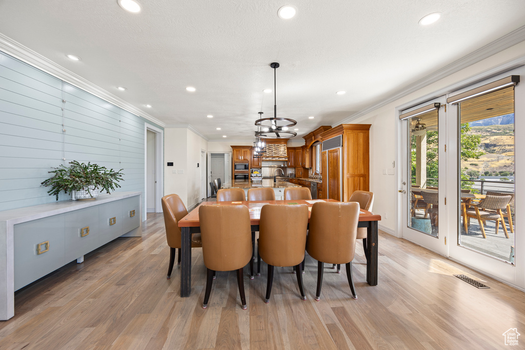 Dining room featuring sink, an inviting chandelier, crown molding, and light hardwood / wood-style flooring