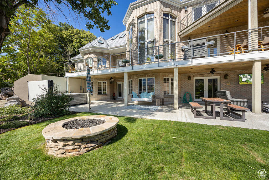 Rear view of property featuring a fire pit, a patio, a balcony, french doors, and ceiling fan