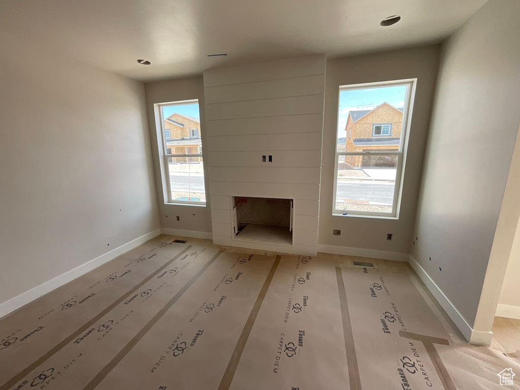 Unfurnished living room with plenty of natural light and a large fireplace