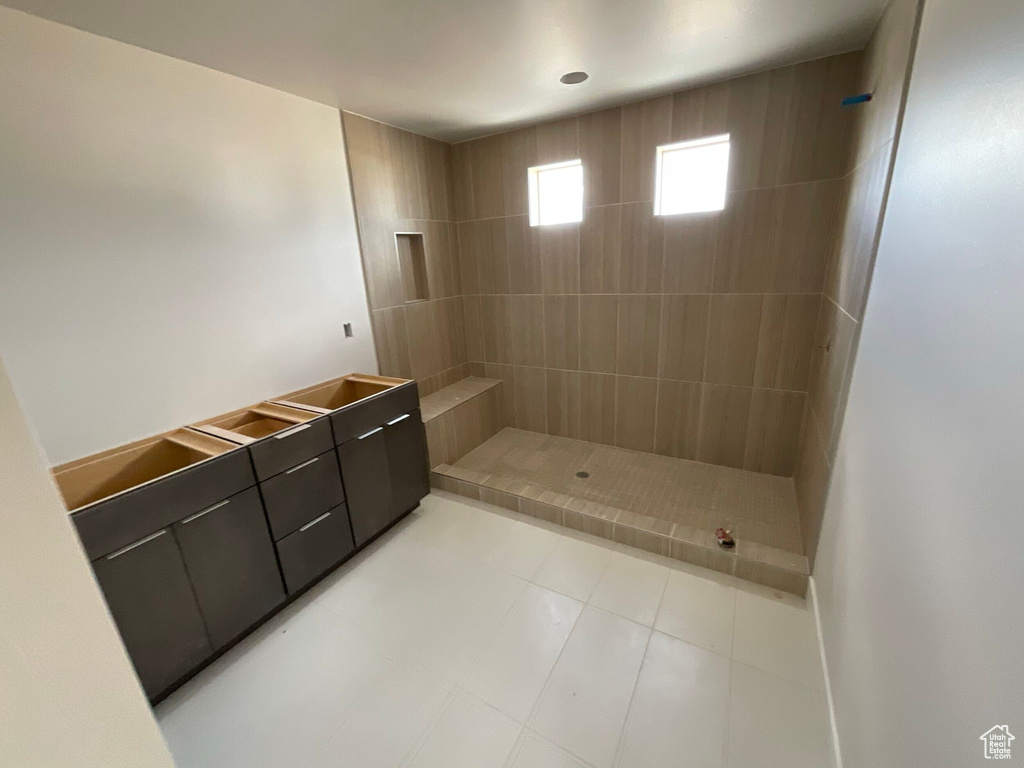 Bathroom with vanity, tile patterned floors, and a tile shower