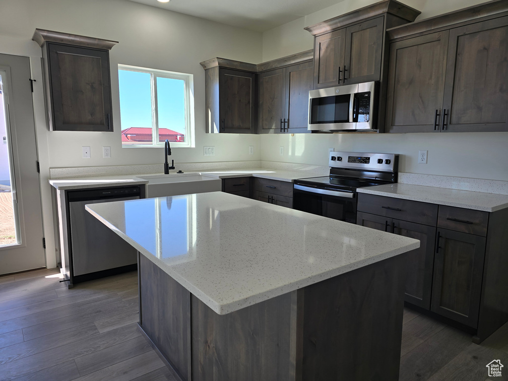 Kitchen featuring appliances with stainless steel finishes, sink, a kitchen island, and dark hardwood / wood-style flooring