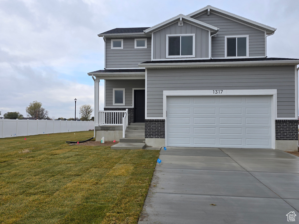 View of front of property featuring covered porch, a garage, and a front lawn