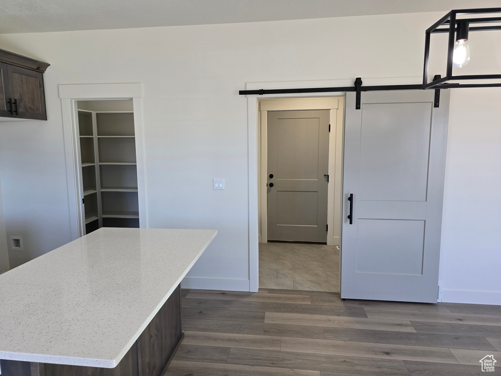 Kitchen with dark brown cabinetry, dark hardwood / wood-style flooring, a barn door, and a kitchen island