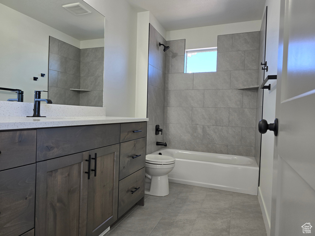 Full bathroom featuring vanity, toilet, tile patterned floors, and tiled shower / bath