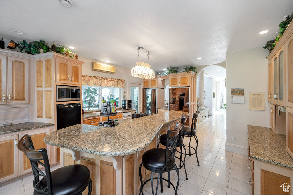 Kitchen featuring a wall mounted AC, light tile patterned floors, stainless steel appliances, a kitchen island, and a breakfast bar area