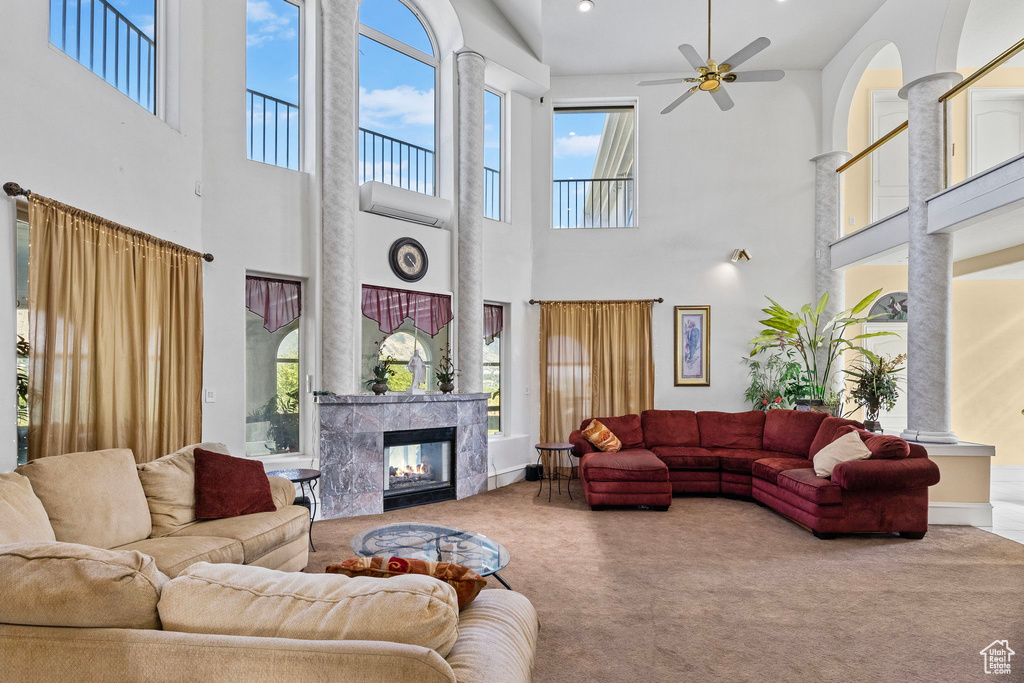 Living room with carpet flooring, ceiling fan, a high end fireplace, and a towering ceiling