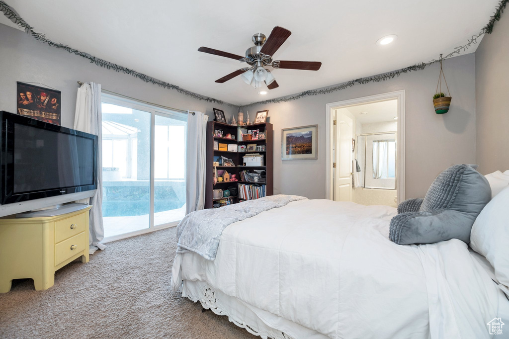 Carpeted bedroom featuring multiple windows, ceiling fan, access to outside, and ensuite bath