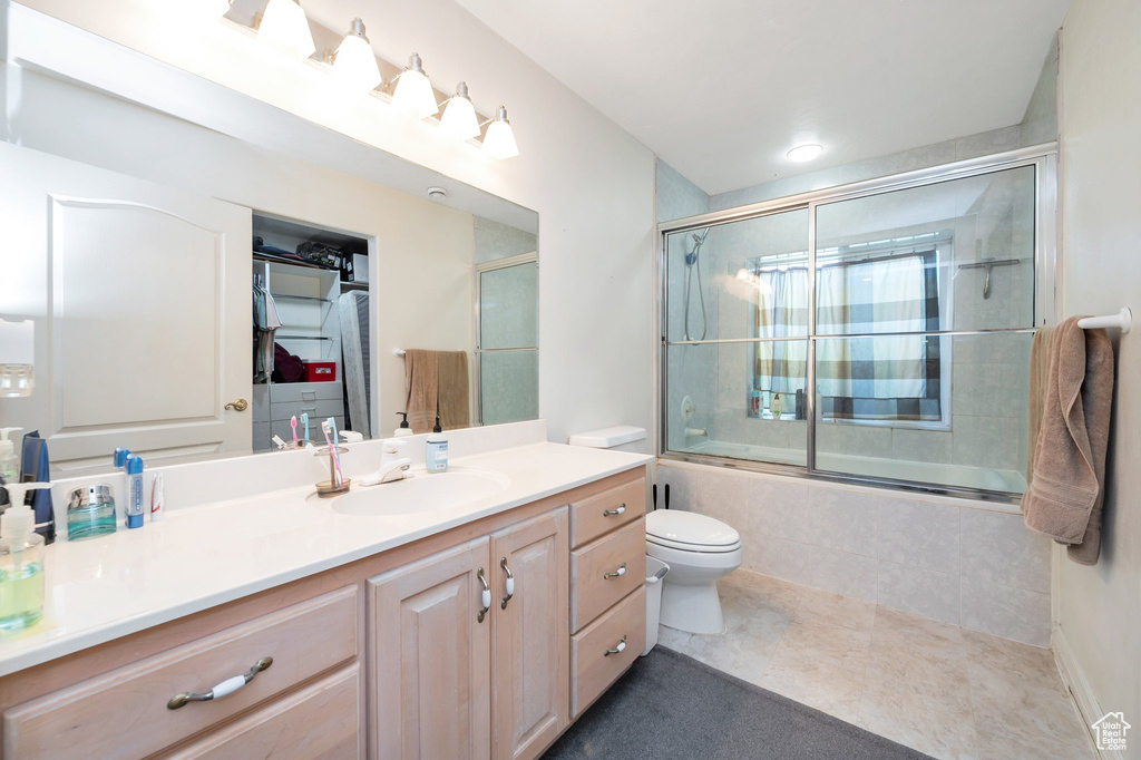 Full bathroom featuring toilet, combined bath / shower with glass door, and vanity