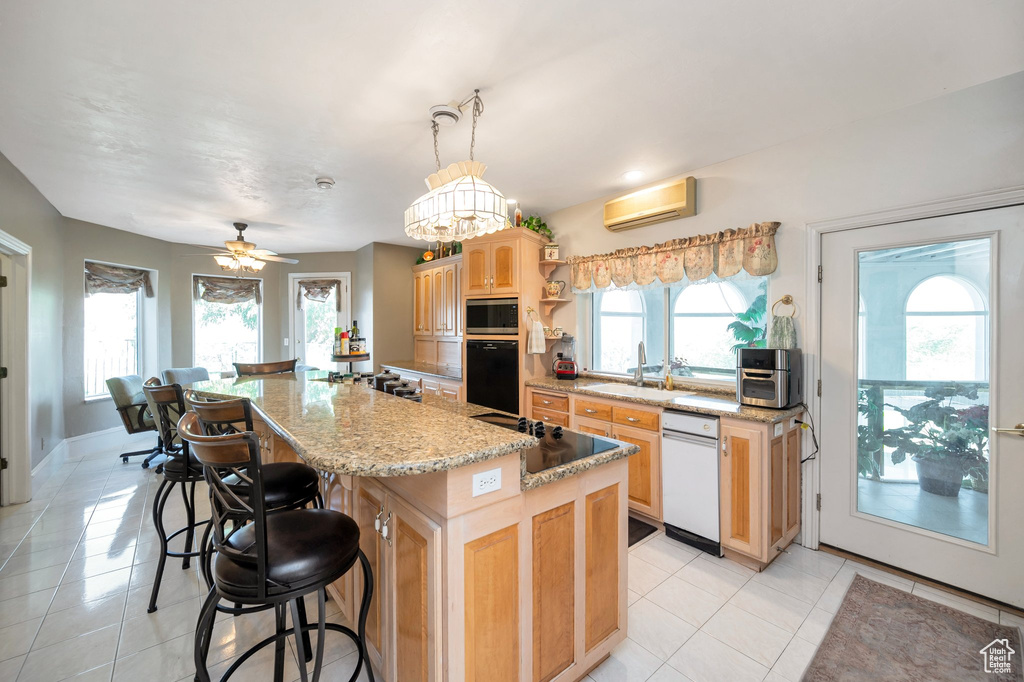 Kitchen featuring a wealth of natural light, a kitchen island, ceiling fan with notable chandelier, and black appliances