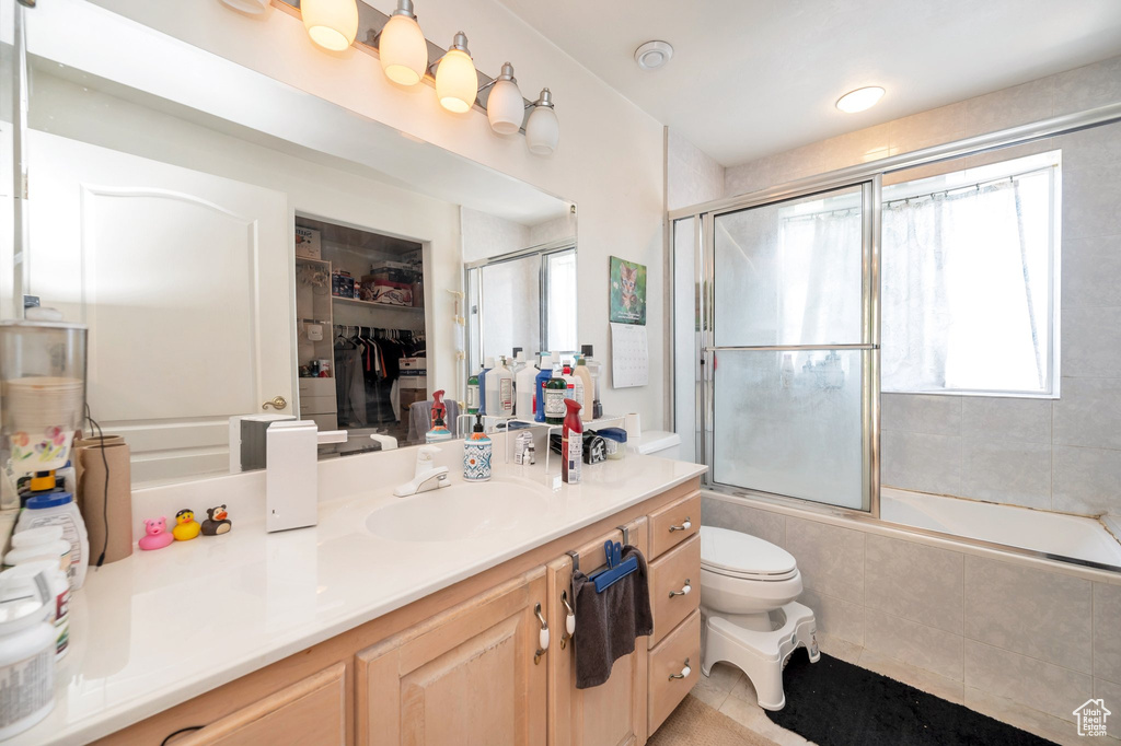 Full bathroom featuring vanity, toilet, tile patterned flooring, and enclosed tub / shower combo