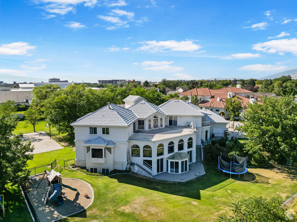 Rear view of property featuring a lawn and a trampoline