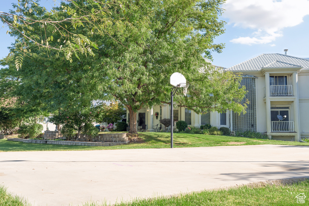 View of front of property with a balcony, basketball court, and a front yard