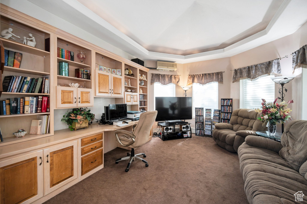 Office area featuring built in desk, carpet flooring, a wall mounted AC, and a raised ceiling