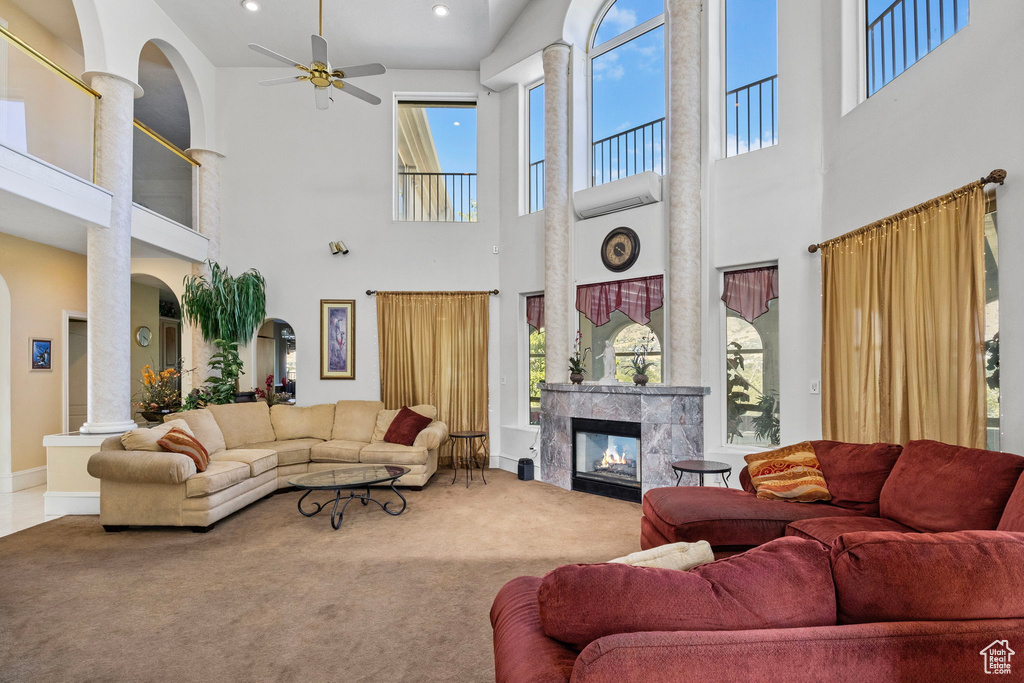 Carpeted living room featuring ceiling fan, a tiled fireplace, and a towering ceiling