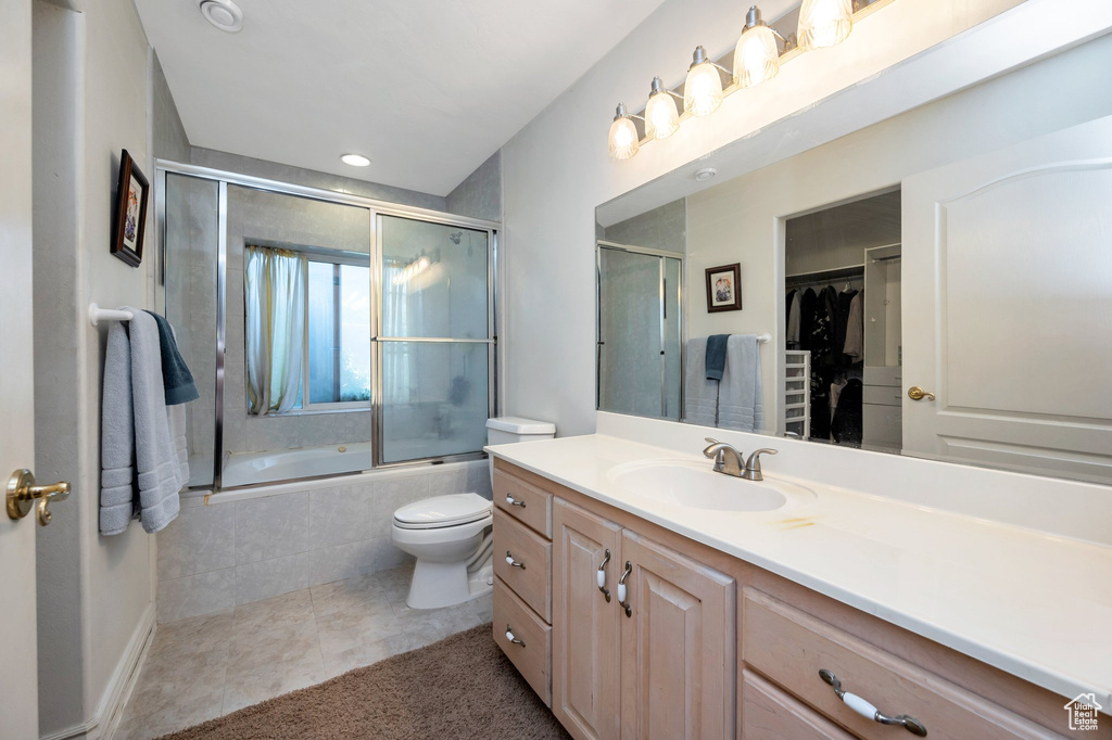 Full bathroom with vanity, toilet, tile patterned floors, and enclosed tub / shower combo