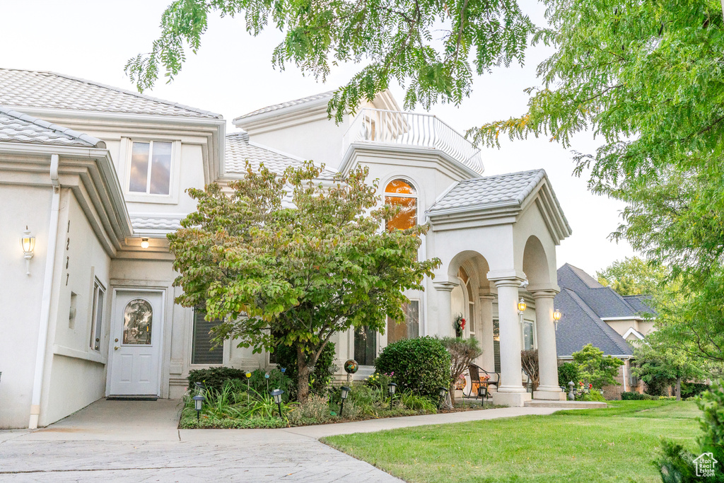 View of front of property featuring a balcony and a front yard