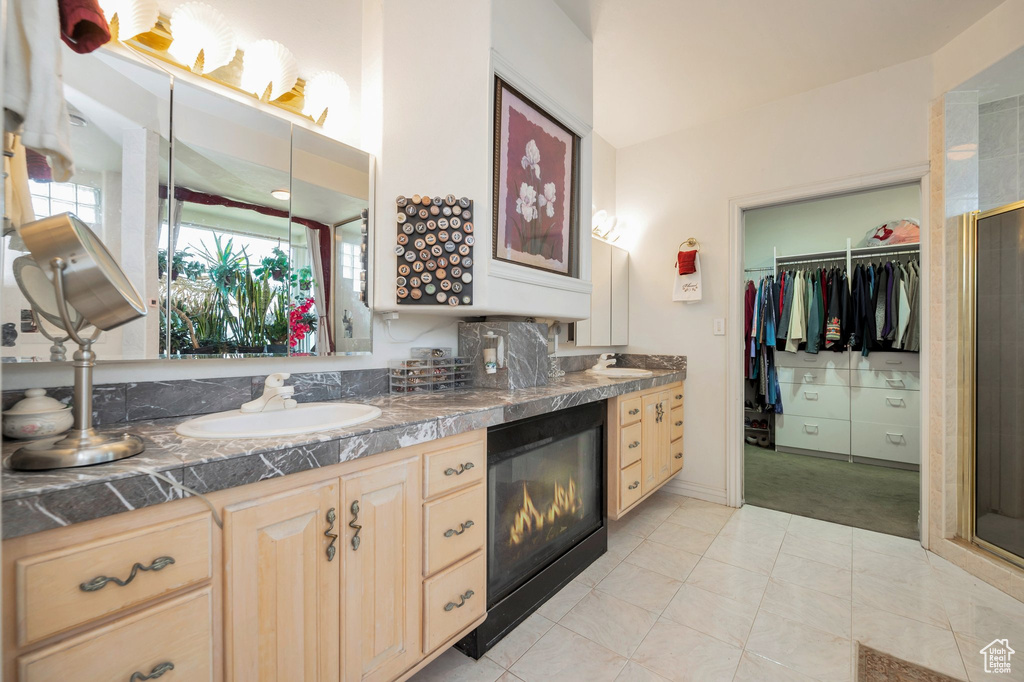 Bathroom featuring tile patterned floors, a shower with shower door, plenty of natural light, and vanity