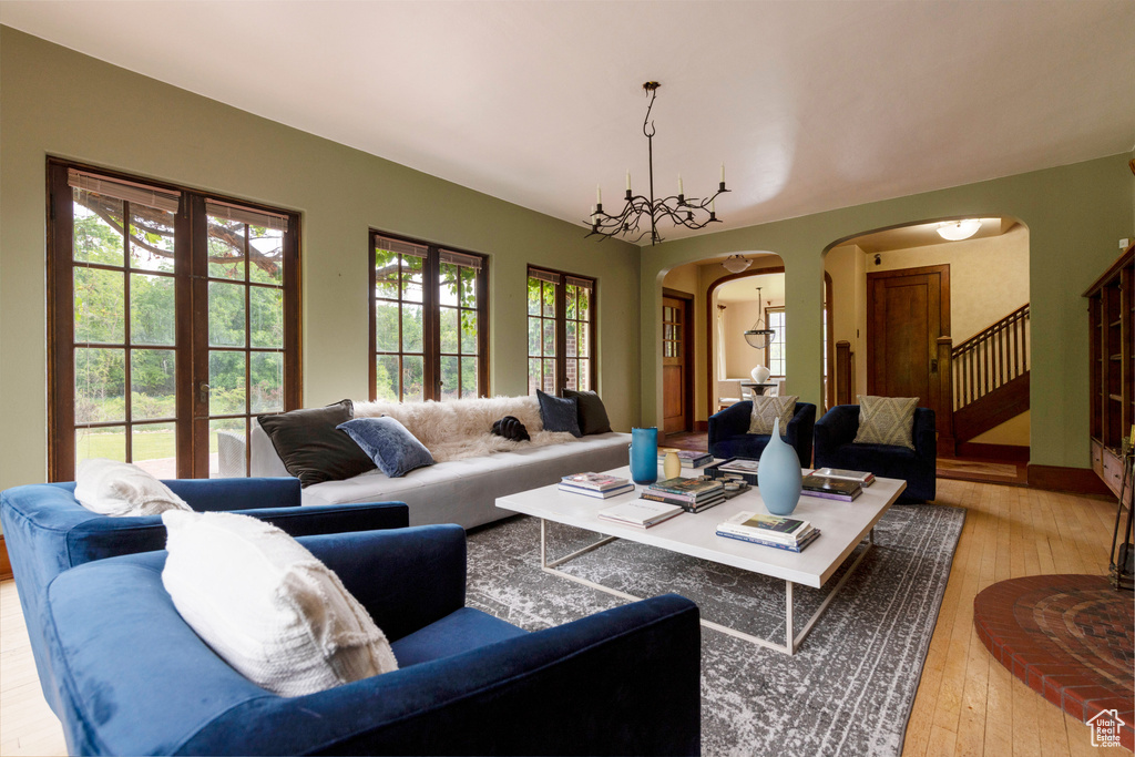 Living room with arched walkways, healthy amount of natural light, hardwood / wood-style floors, and stairway