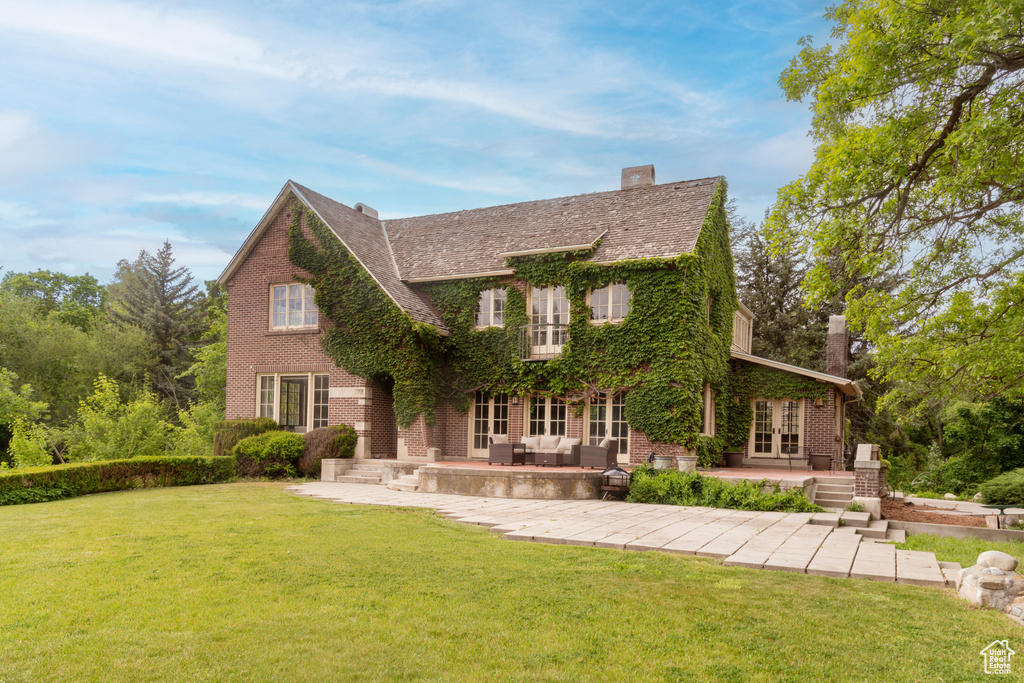 View of front of house with french doors, a patio area, brick siding, and a front lawn