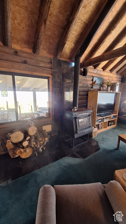 Carpeted living room featuring a wood stove and vaulted ceiling with beams