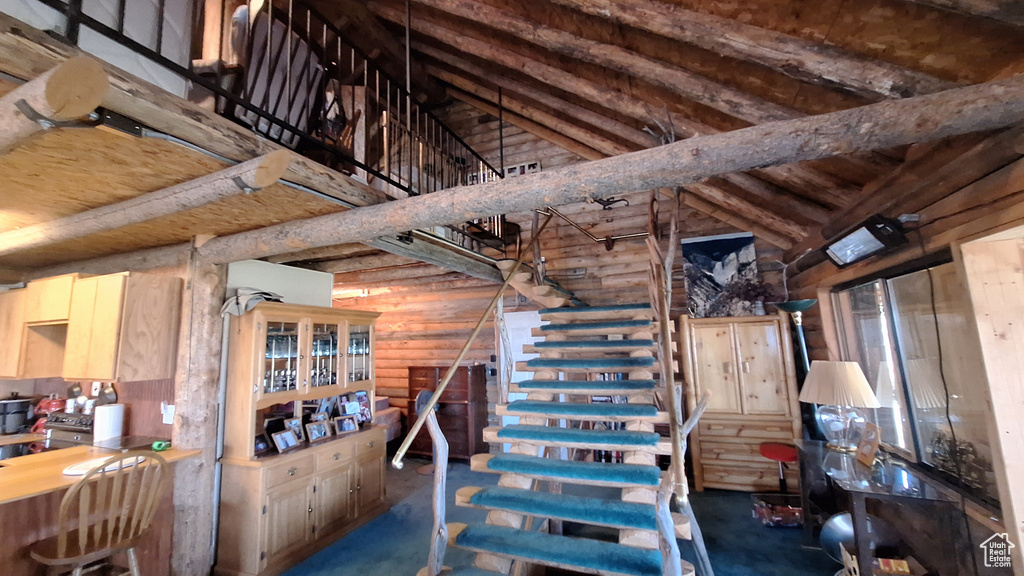 Interior space with rustic walls, high vaulted ceiling, beam ceiling, and light brown cabinetry