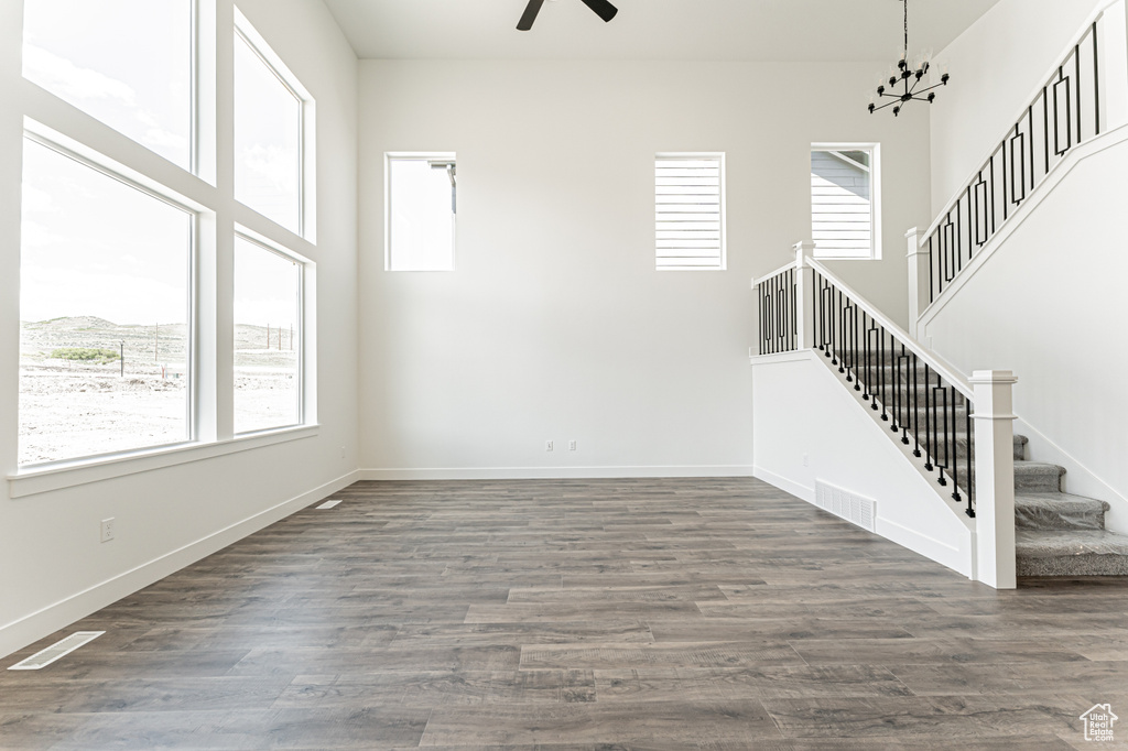 Unfurnished living room with stairs, a ceiling fan, wood finished floors, and baseboards