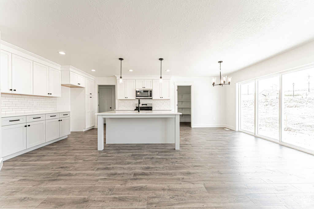 Kitchen featuring stainless steel appliances, a chandelier, recessed lighting, decorative backsplash, and a textured ceiling