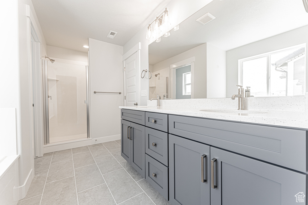 Bathroom with double vanity, a stall shower, and baseboards