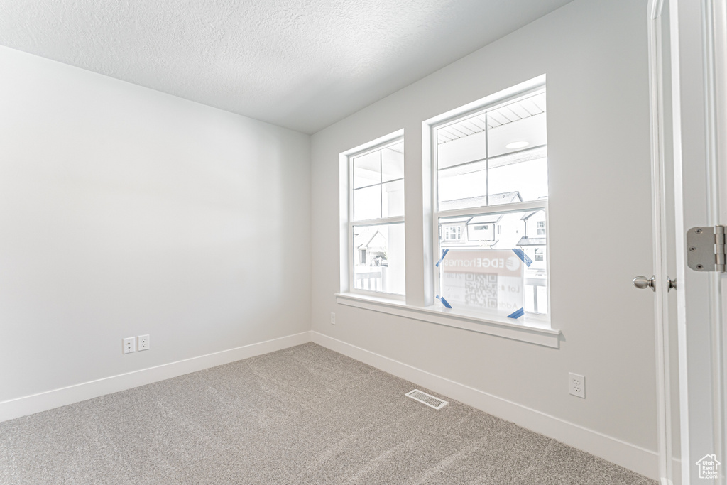 Carpeted empty room featuring baseboards and a textured ceiling