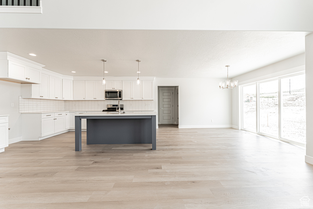 Kitchen with appliances with stainless steel finishes, a chandelier, light countertops, backsplash, and baseboards