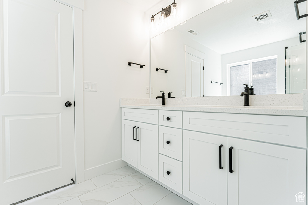 Full bathroom with marble finish floors, double vanity, and baseboards
