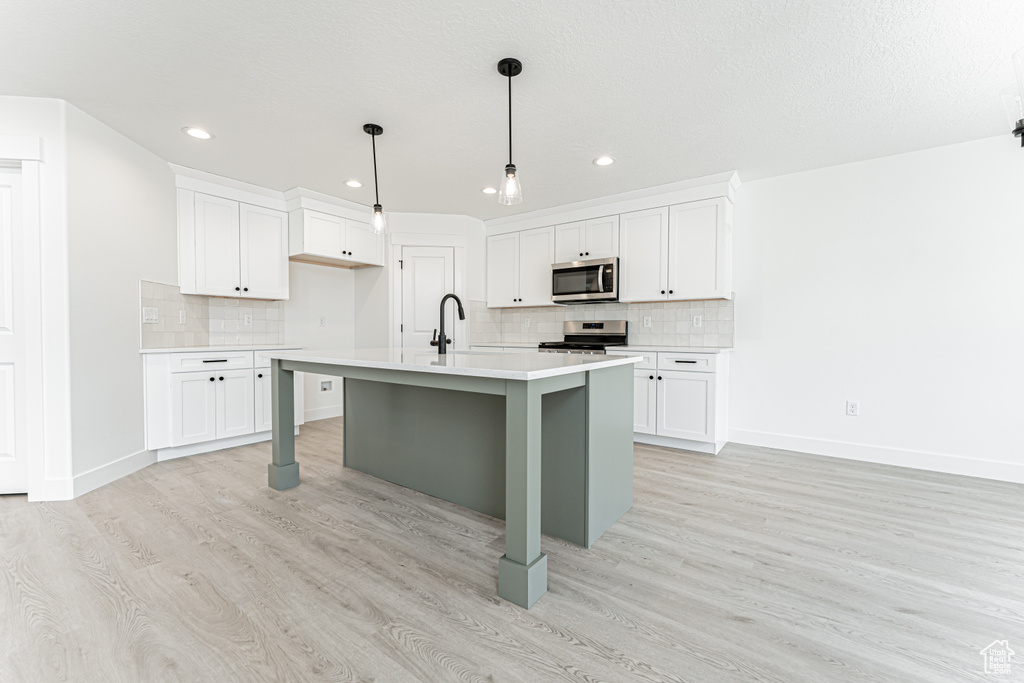 Kitchen featuring appliances with stainless steel finishes, light countertops, light wood finished floors, recessed lighting, and baseboards