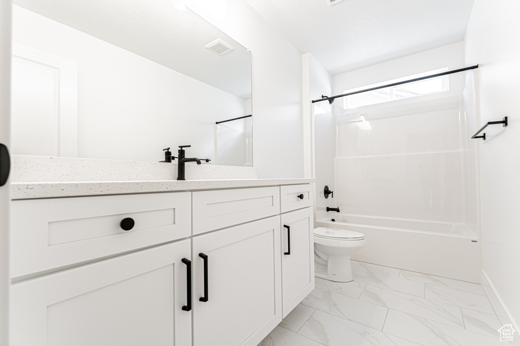 Bathroom featuring bathing tub / shower combination, vanity, toilet, and marble finish floors
