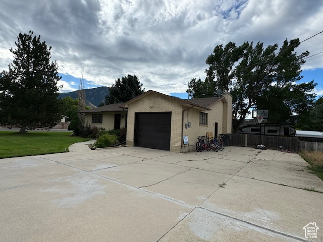 View of property exterior with a garage, a mountain view, and a lawn