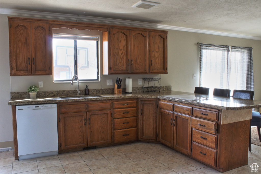 Kitchen featuring ornamental molding, light tile patterned floors, kitchen peninsula, white dishwasher, and sink