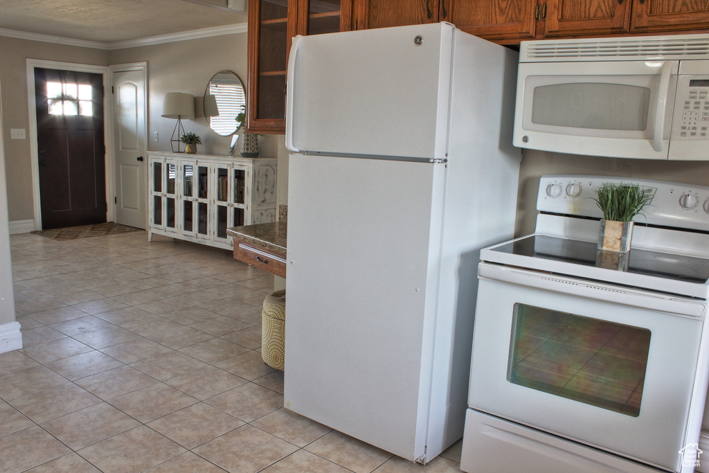 Kitchen featuring crown molding, white appliances, and light tile patterned floors