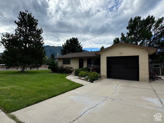 Ranch-style house with a mountain view, a front yard, and a garage