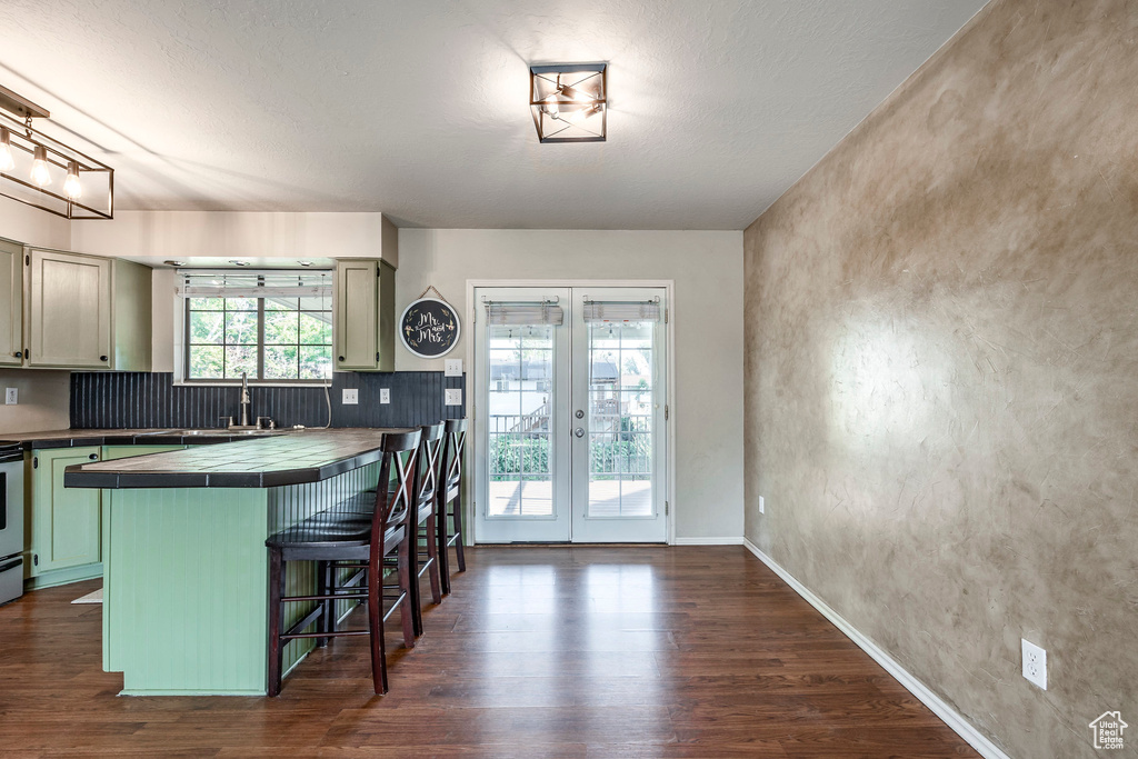 Kitchen featuring a kitchen breakfast bar, kitchen peninsula, dark wood-type flooring, and tile counters