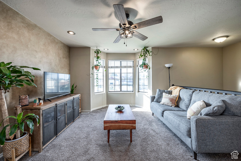 Carpeted living room with a textured ceiling and ceiling fan