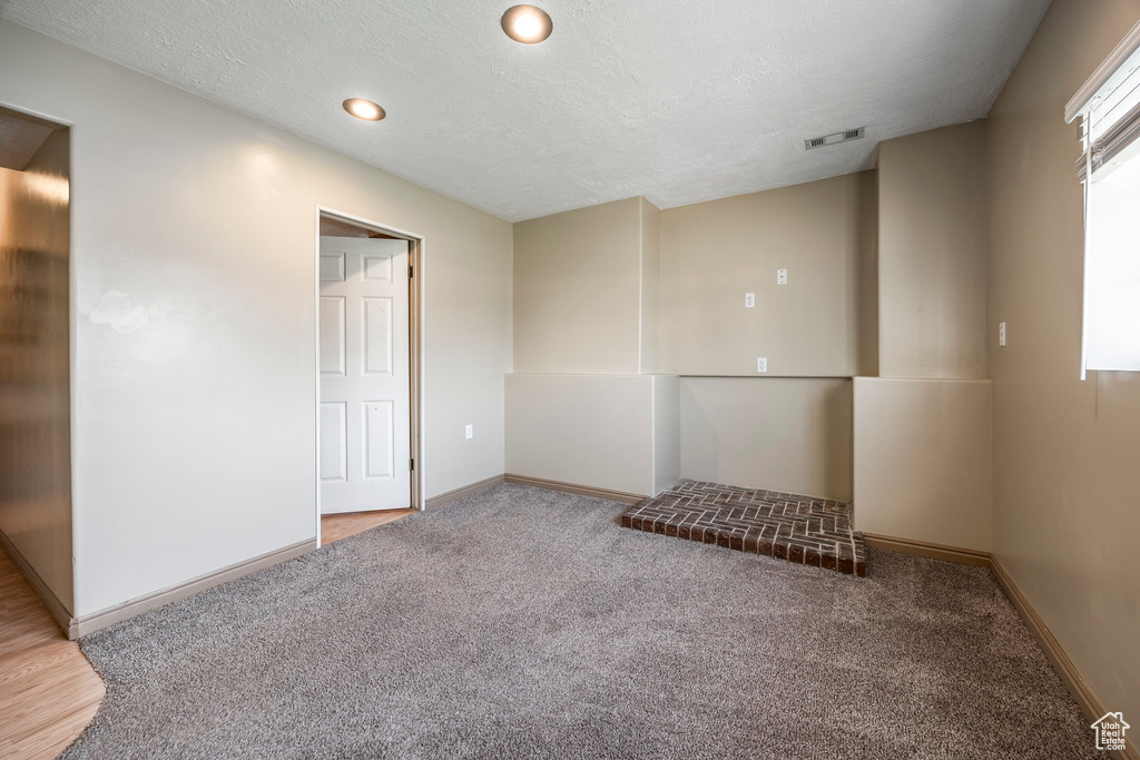 Unfurnished room with a textured ceiling and light colored carpet