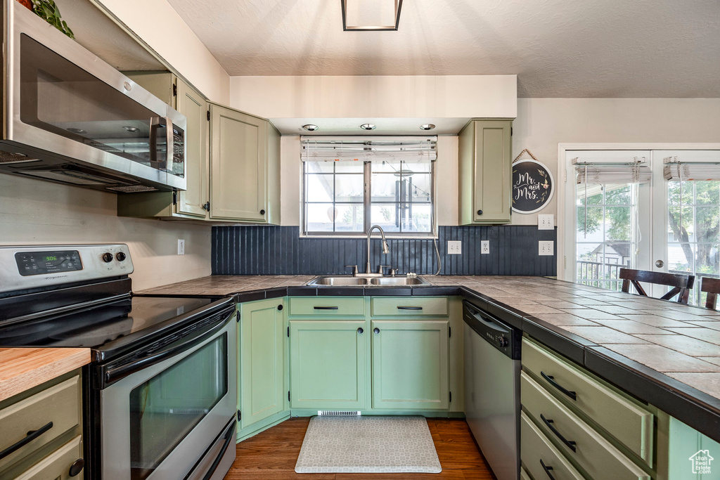 Kitchen featuring appliances with stainless steel finishes, dark hardwood / wood-style flooring, a wealth of natural light, and sink