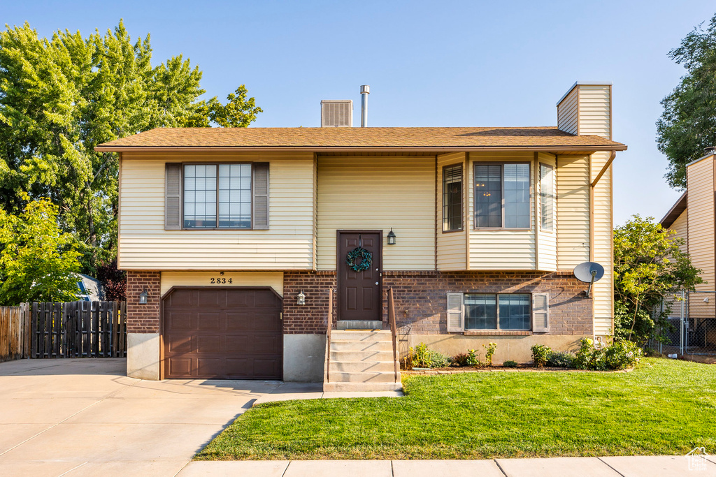 Split foyer home featuring a garage and a front lawn