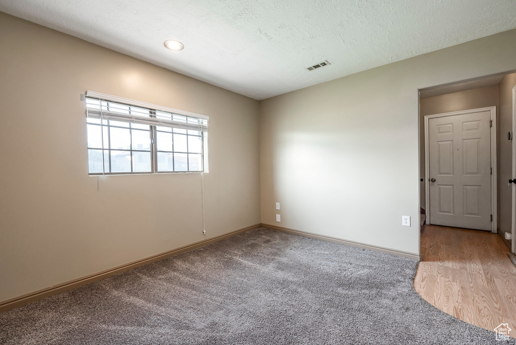 Empty room featuring a textured ceiling and light colored carpet