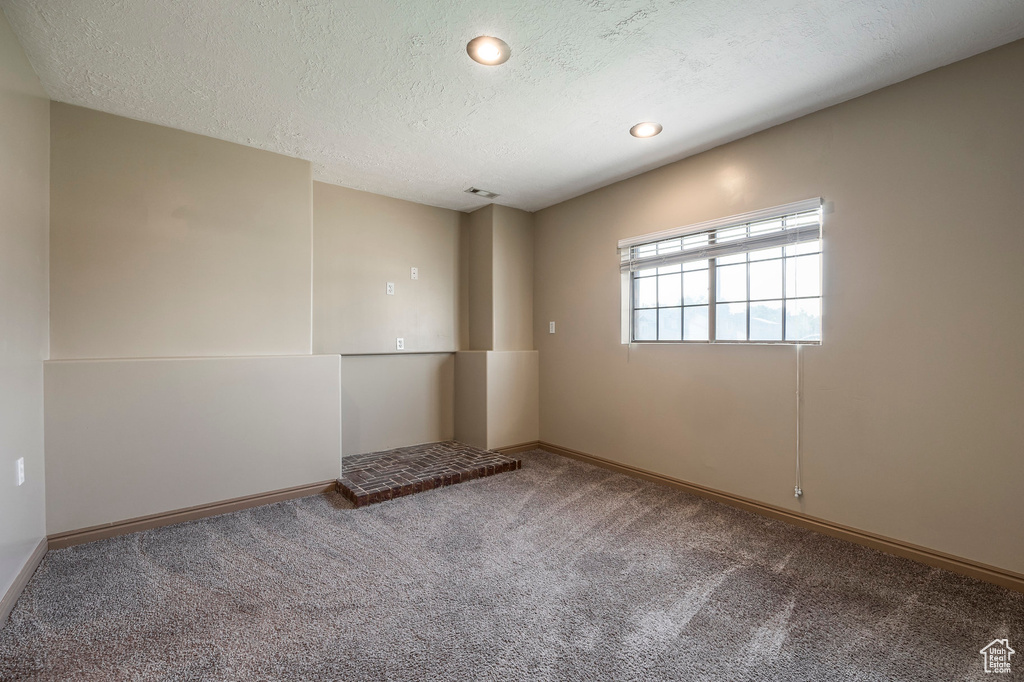 Carpeted spare room with a textured ceiling