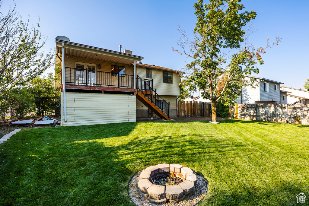 Back of house featuring a fire pit, a lawn, and a deck