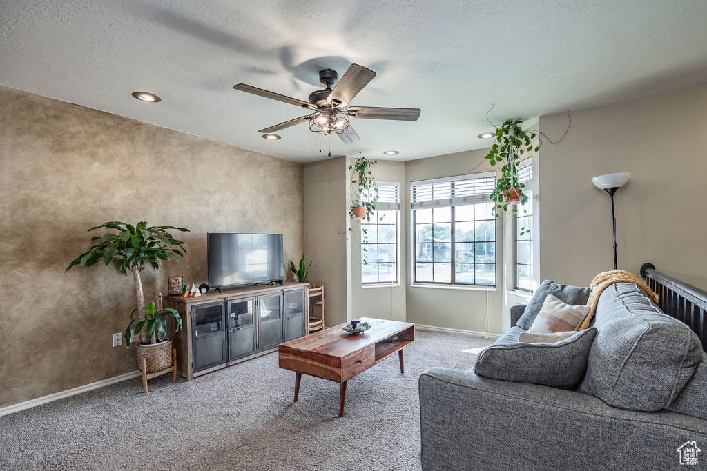 Carpeted living room featuring a textured ceiling and ceiling fan