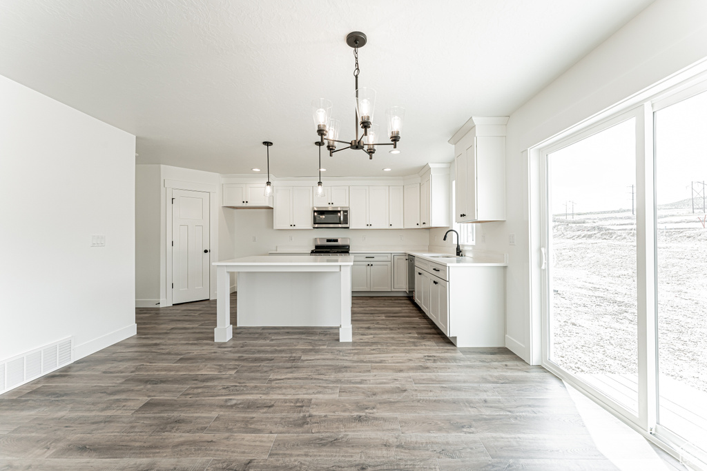 Kitchen featuring appliances with stainless steel finishes, a chandelier, plenty of natural light, a kitchen island, and recessed lighting