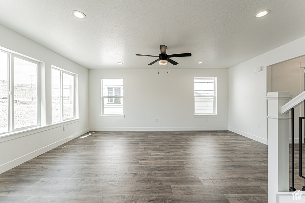Unfurnished living room featuring healthy amount of natural light, ceiling fan, recessed lighting, baseboards, and dark wood-style flooring