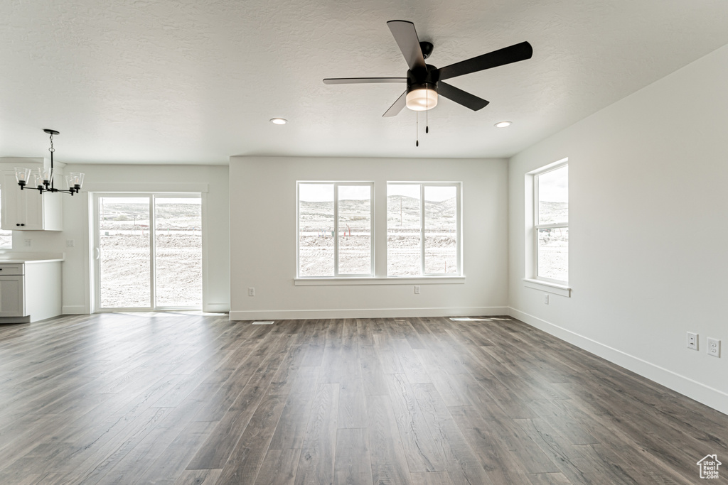 Unfurnished living room with a chandelier, dark wood-type flooring, ceiling fan, baseboards, and recessed lighting