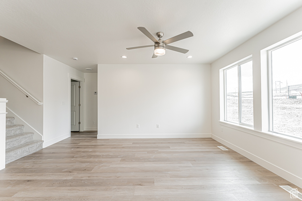 Spare room featuring stairway, ceiling fan, light wood-type flooring, recessed lighting, and baseboards